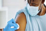 Photo of a person wearing a surgical mask receives a vaccine injection