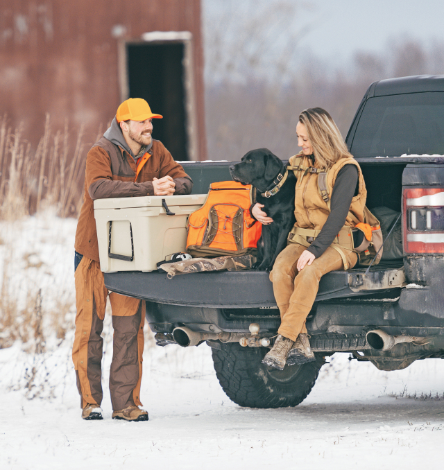 Page couverture du Résumé des règlements de la chasse de l'Ontario 2024 montrant un homme et une femme assis avec leur chien et leur matériel de chasse sur le hayon de leur camionnette