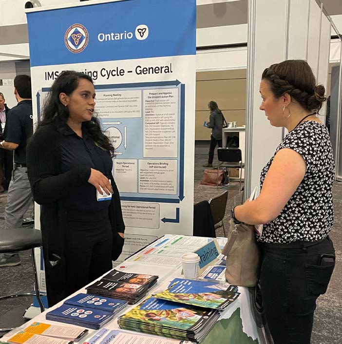 Two people standing next to a table and looking at brochures