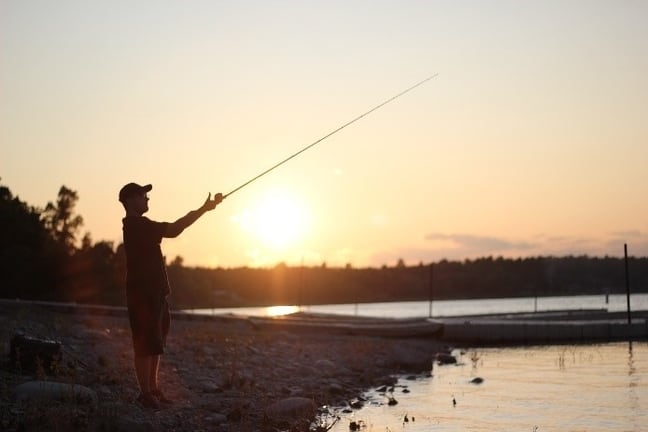 Image of man casting from shore during sunset.