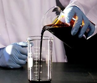 Photo montrant un technicien en laboratoire versant de la biohuile d’un bécher dans un autre