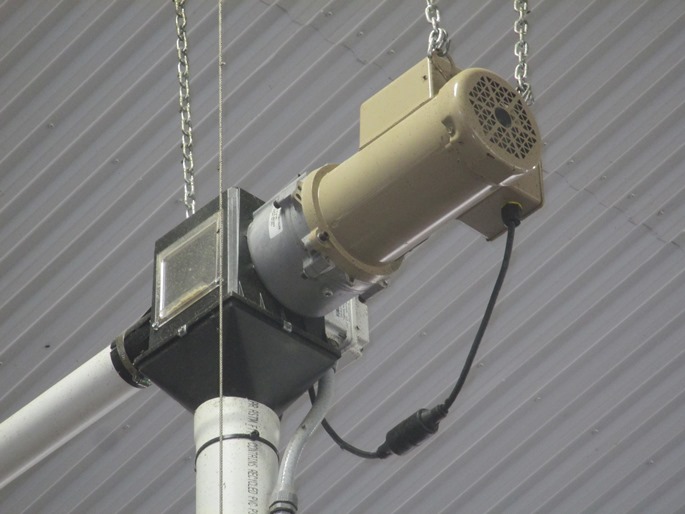 This is a photograph of a compressor installed inside a compressor room in a barn. There is an electrical disconnect panel installed on the wall of the room. The disconnect panel is rated for use in wet and dusty environments. The cable supplying electrical power from the disconnect panel to the compressor is hard-wired. A plug and receptacle is not used. Sealing grommets are installed around the cable to seal the point where it enters the compressor and disconnect panel.