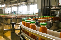 Juice in glass bottle on conveyor belt at a food processing plan.