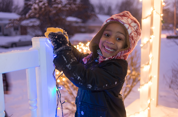 a happy child setting up Christmas light