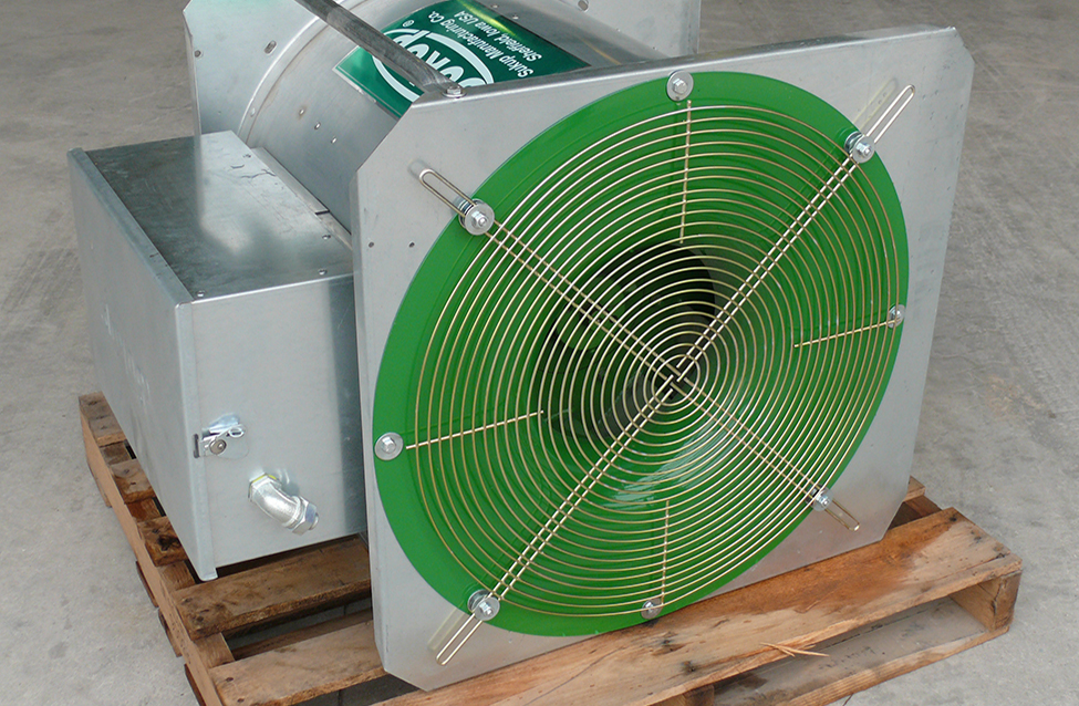 Photographie d’un ventilateur centrifuge aligné sur une palette de bois. L’air pénètre dans une ouverture circulaire grillagée à l’extrémité du ventilateur. Le ventilateur et le moteur électrique sont fixés ensemble.