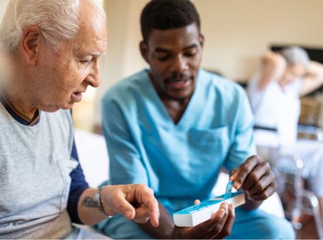 Un travailleur de la santé aide une personne âgée à prendre ses médicaments