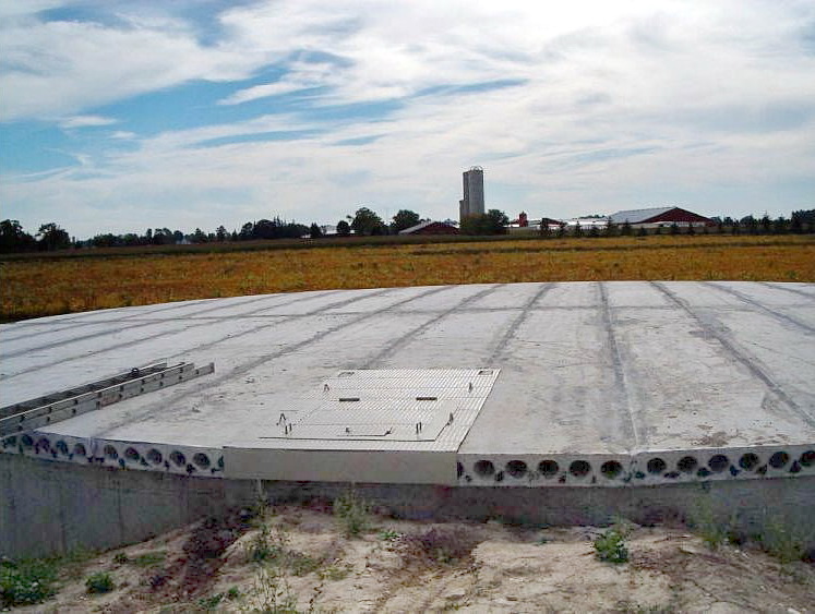 A circular concrete manure tank with an impermeable flat concrete cover
