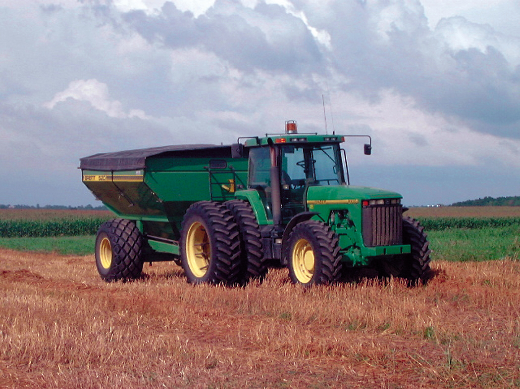 A tractor pulling a grain wagon in a harvested grain field 