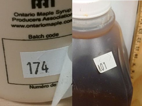 Image of two side-by-side maple syrup containers with stickers displaying a number 174 (left) and A01 (right) as custom lot codes. 