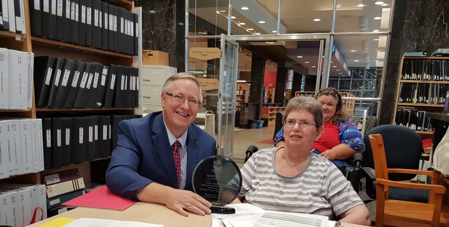 Cornwall Municipal Heritage Committee member presents an award to a homeowner at the Cornwall Community Library