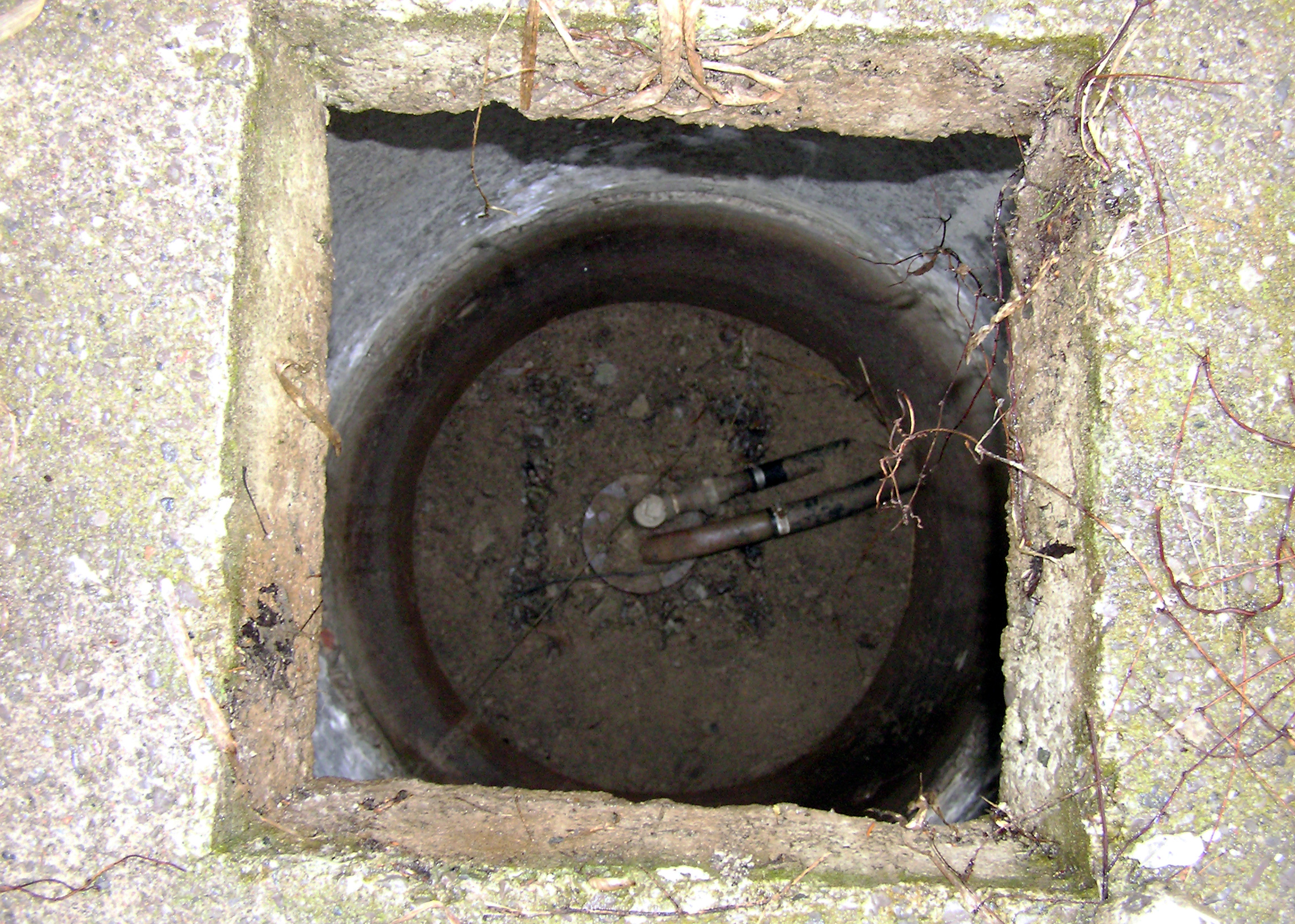 A top view of a circular well sitting inside an old large diameter well