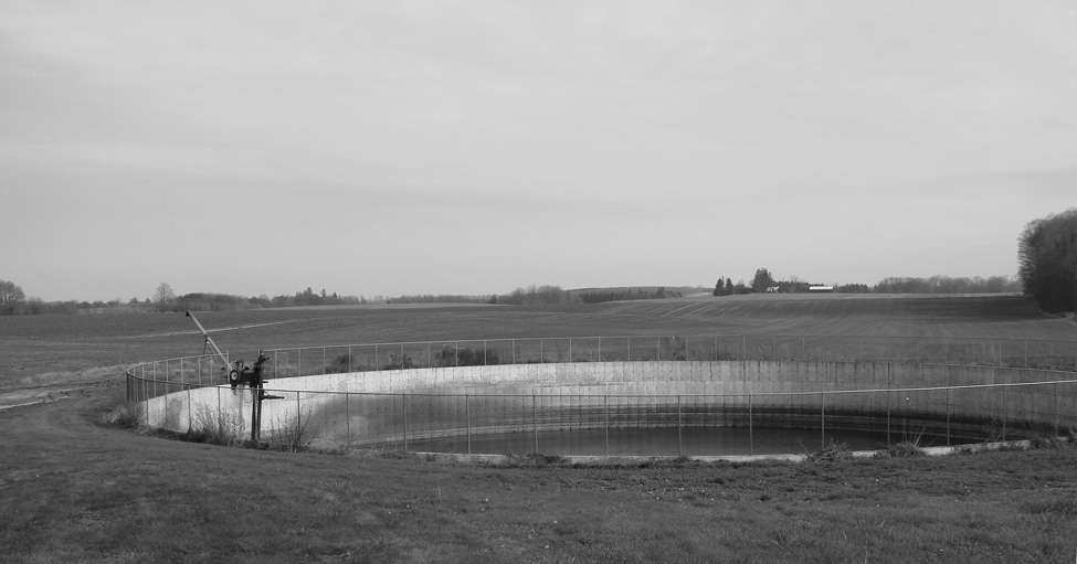 A large circular manure storage tank situated in a pasture