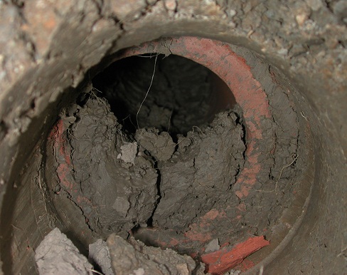 This photo shows a drain pipe containing a significant amount of sediment.