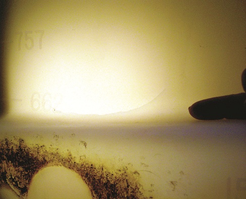 Close-up photo of polyethylene tank wall being candled from inside showing crack.