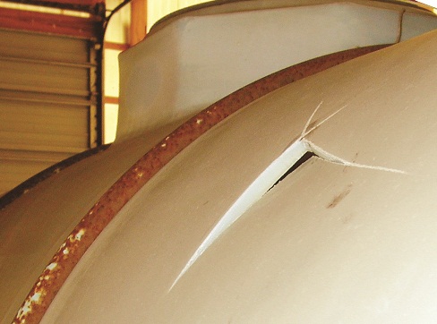Photo of the same tank after it was struck with a baseball bat in area that had been previously coloured to determine the brittleness of polyethylene. The tank failed, as evidenced by the break in the sidewall.