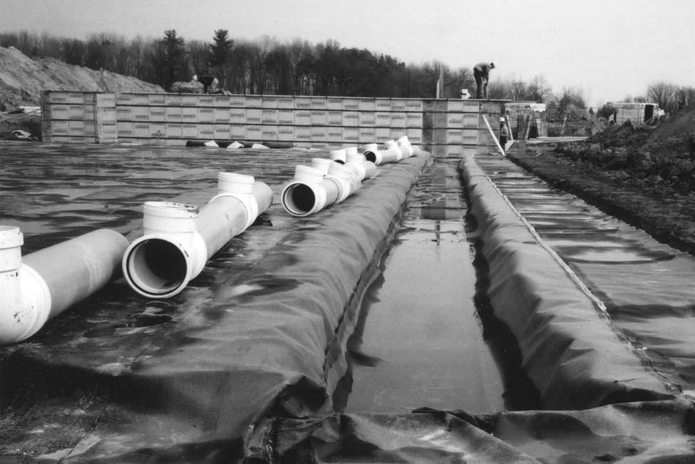 PVC pipe sections lying to the side of a trench that will eventually be connected to form a secure liquid manure transfer system from the in-barn tank to the external manure storage