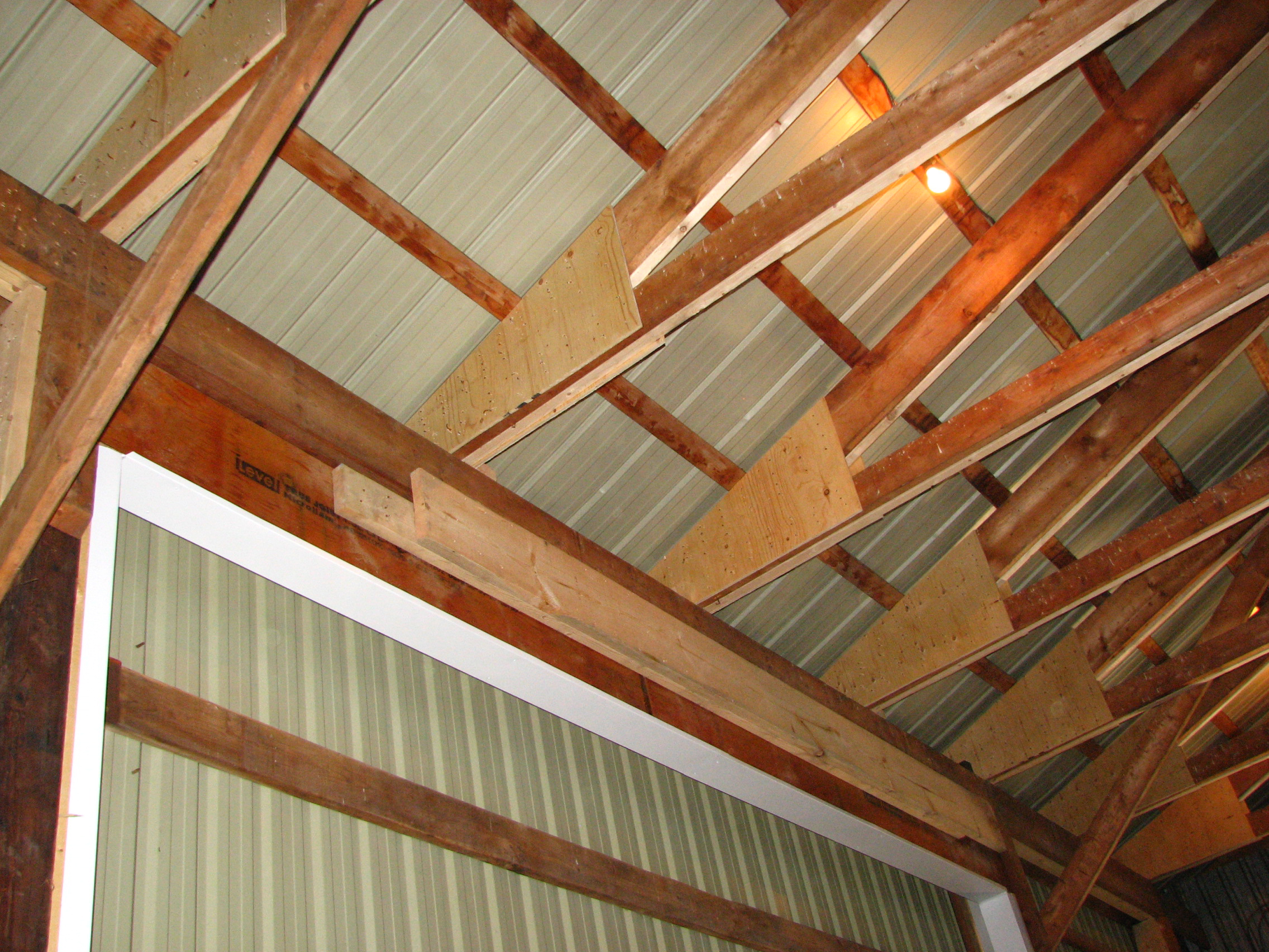 additional bracing, at the joints and chords, that was required to reinforce the beams in a storage shed. The newer bracing material (wood) is lighter in colour than the existing braces.
