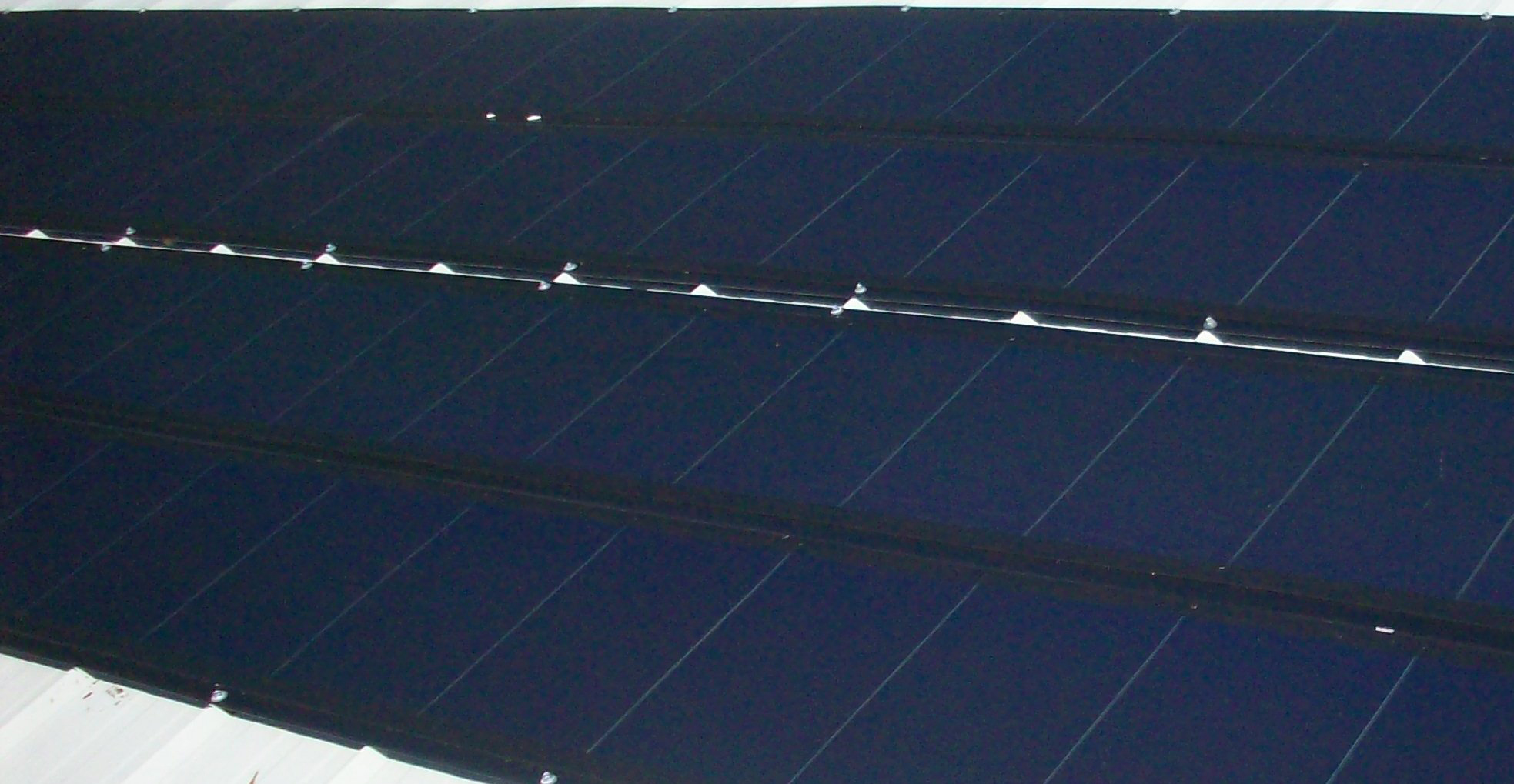 Photos d’une installation solaire à couches minces; les modules ont été appliqués directement sur le toit.