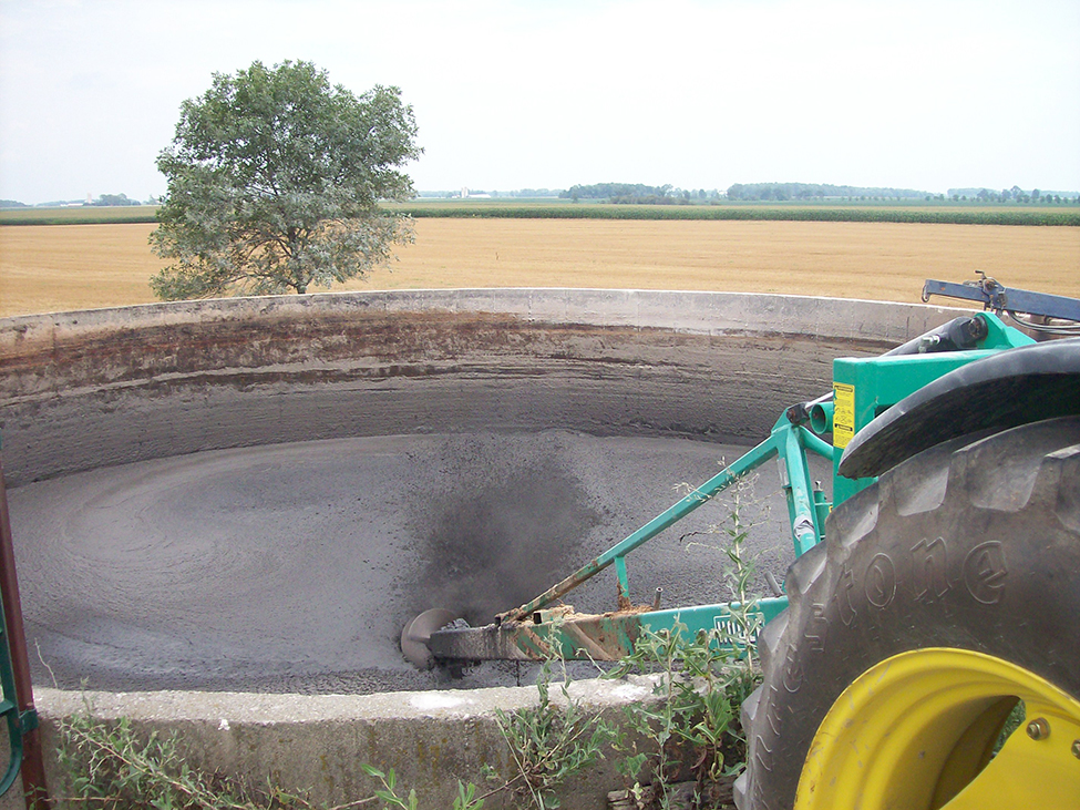 A permanent, circular, concrete tank filled with liquid manure