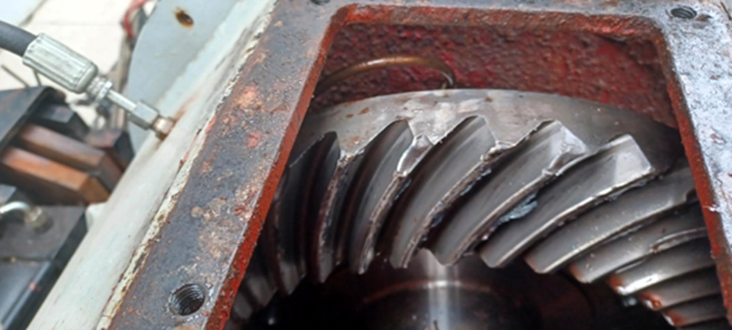 The hoist reduction gear inspection cover is removed, and the lubricating oil supply system to the bearing consists of a hydraulic hose and a copper line routed to the bearing race