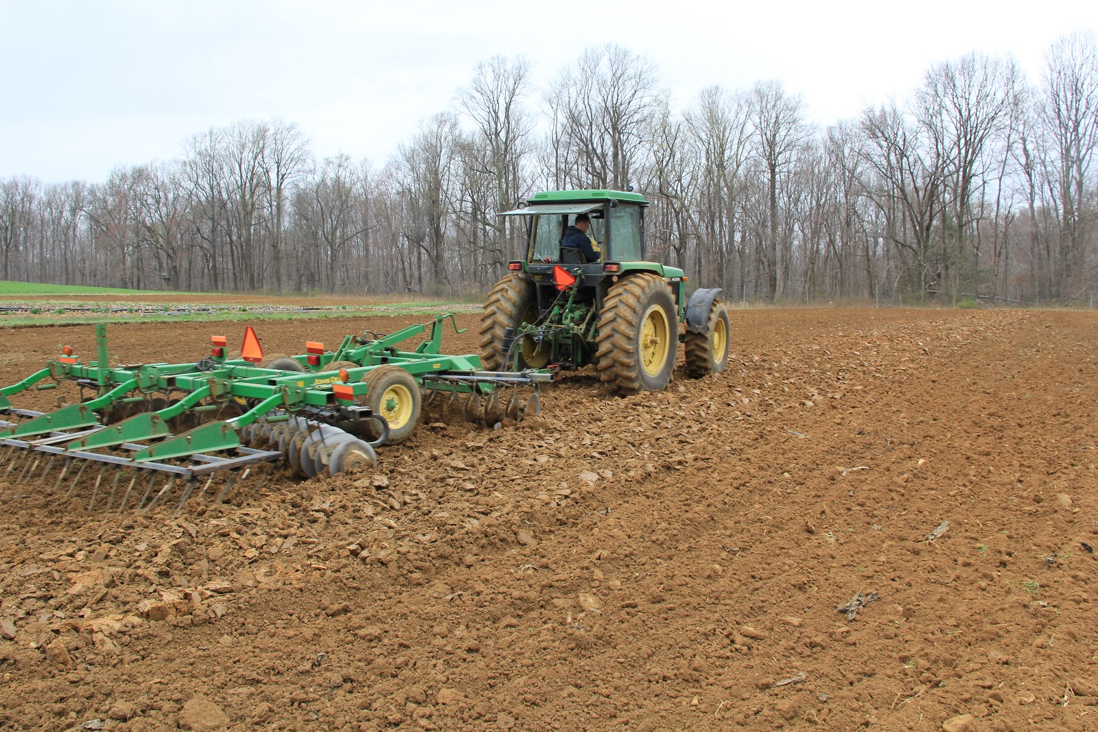 Tracteur travaillant le sol vers le haut et vers le bas d’un champ en pente.