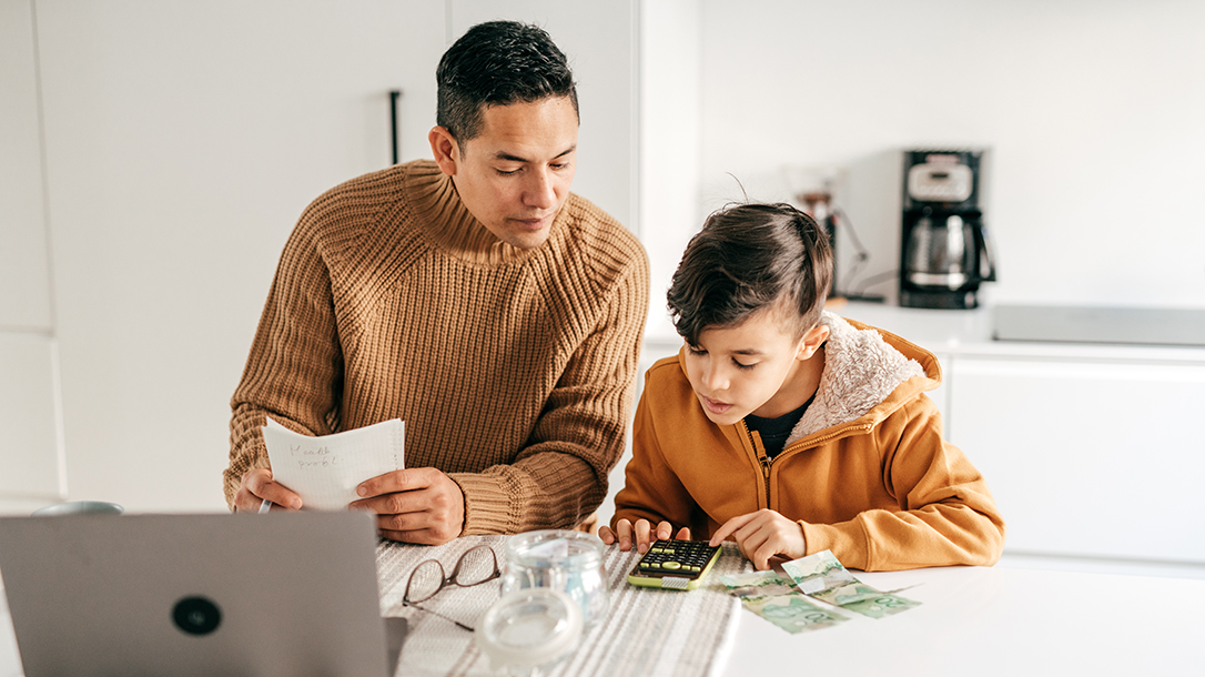 Parent and child going over household bills at the kitchen table