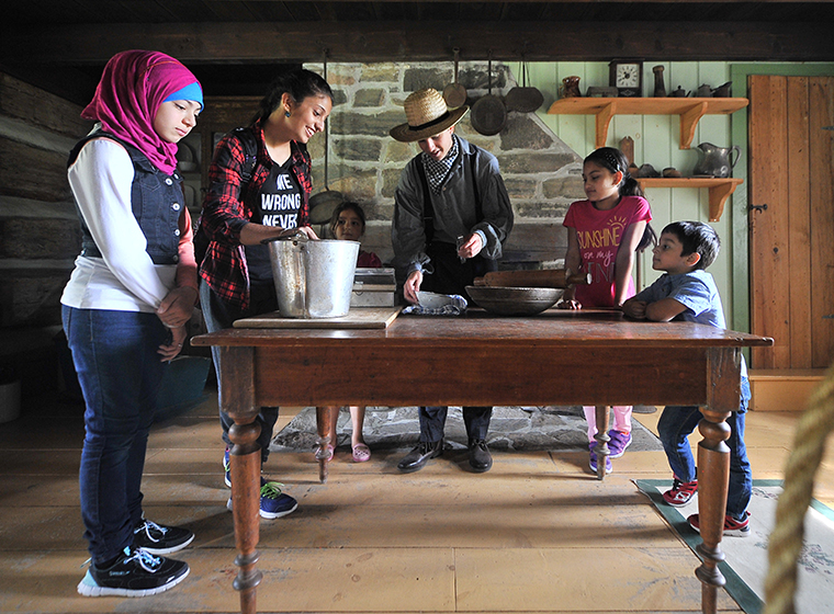 Diverse group, two young adults and three children, participating in cooking demonstration at Simcoe County Museum.