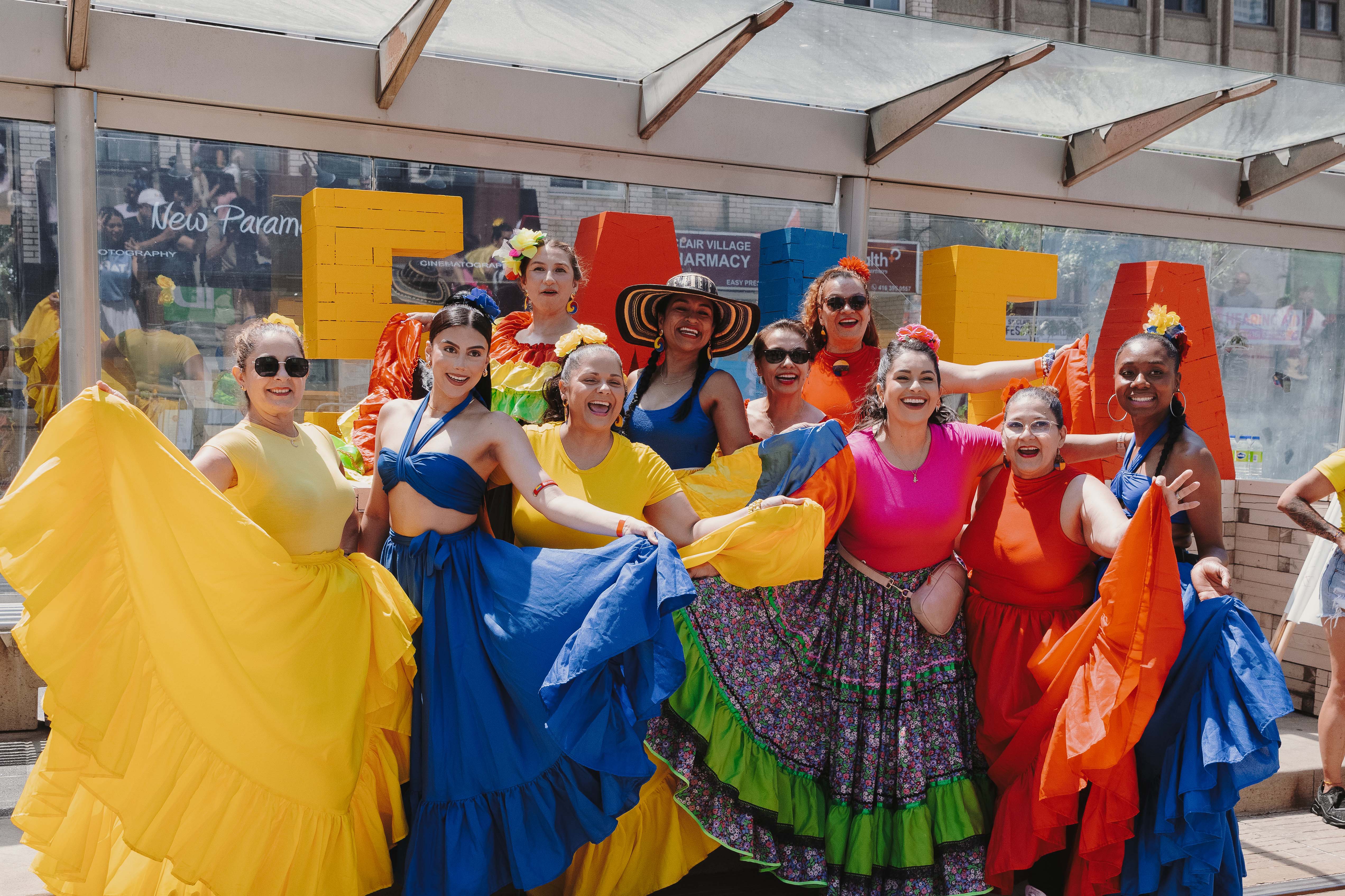 Group of dancers in bright, flowing dresses pose together at Toronto Salsa on St. Clair festival.