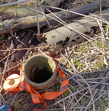 A rusted pipe laying on the ground and a well casing sticking out of the ground. These are both signs that a well could be present.