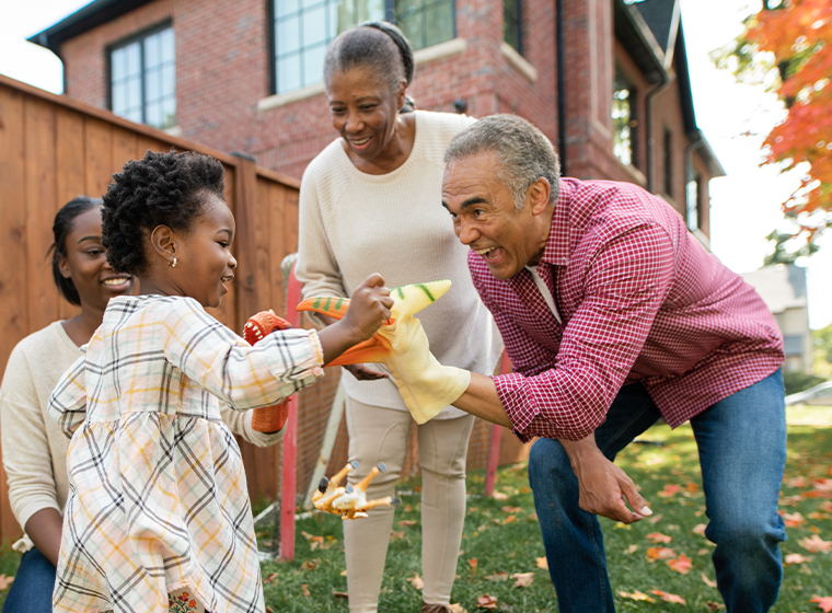 Two older adults playing outside as a family with a child.